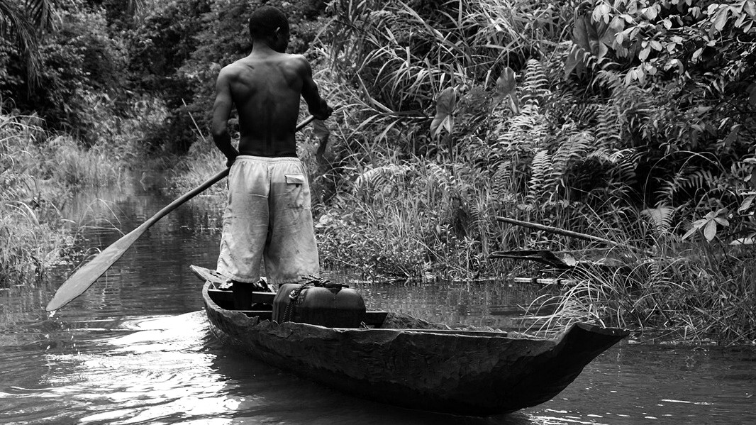 A canoeist moving through a narrow waterway enclosed by dense vegetation