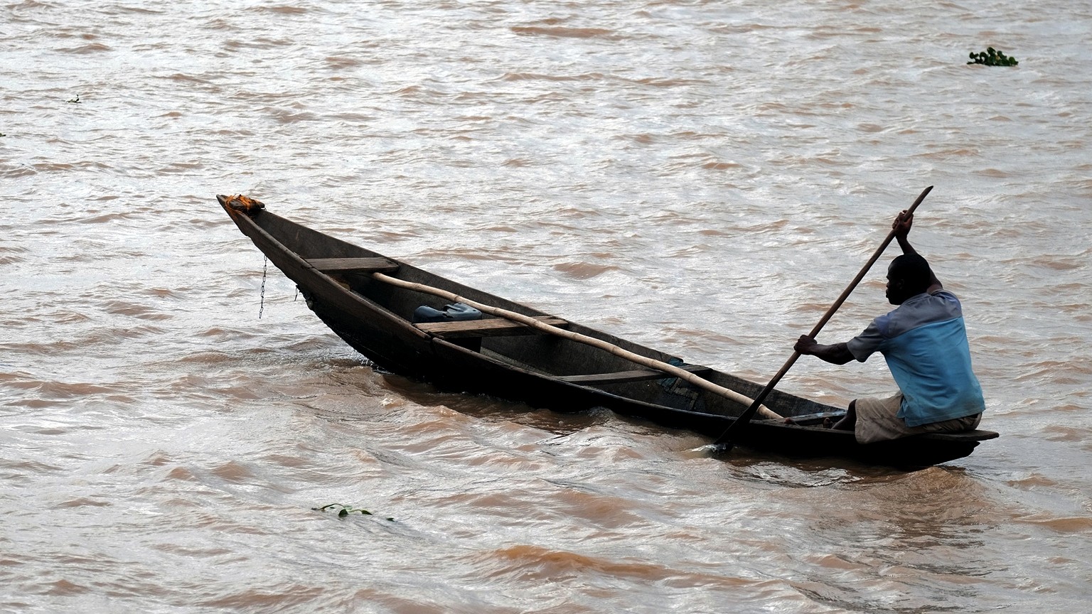 A canoeist guiding a long wooden canoe across open water