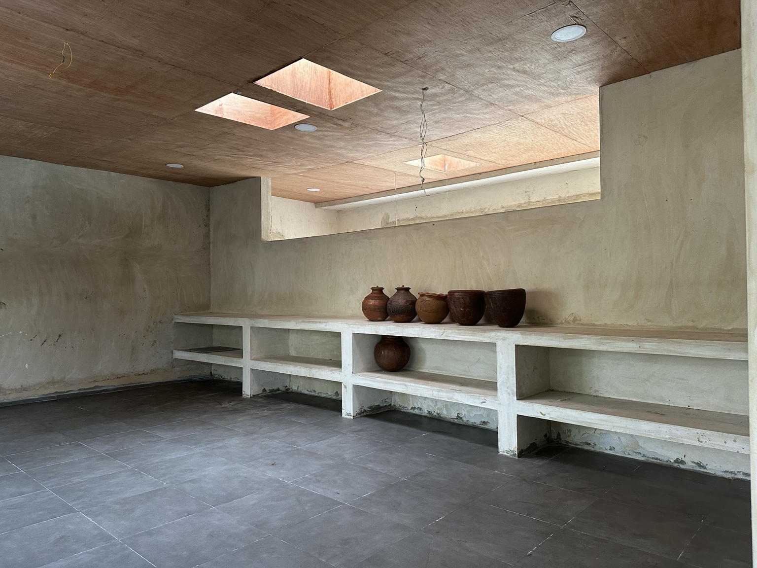 Interior room with clay vessels, built-in shelving and timber ceiling